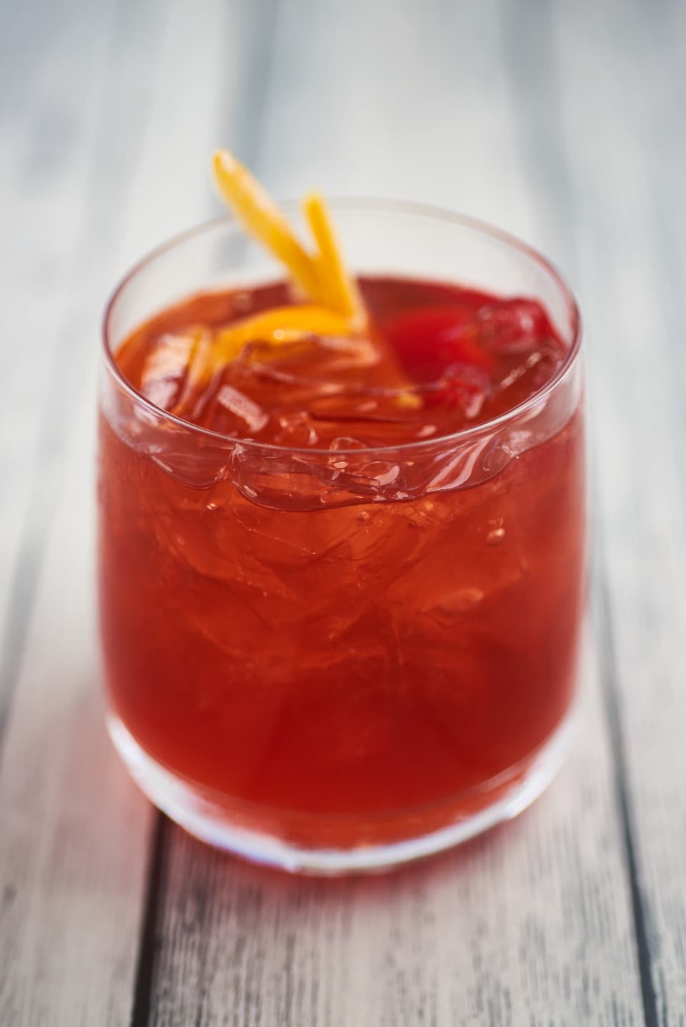 A tall glass of Chapman with orange peel and ice