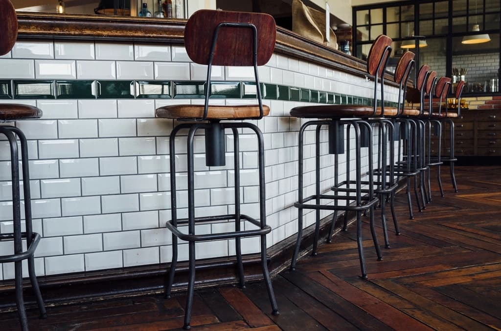 White subway tiles and leather bar stools along a cafe counter