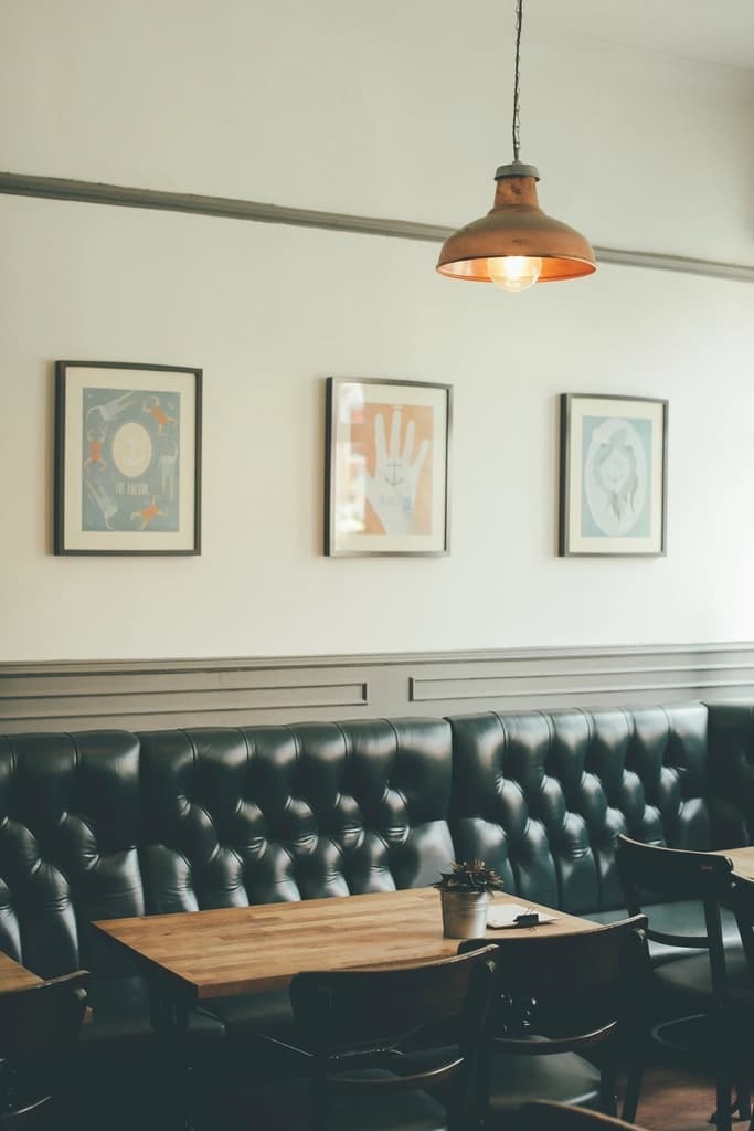 Deep green leather banquettes beneath a copper pendant lamp