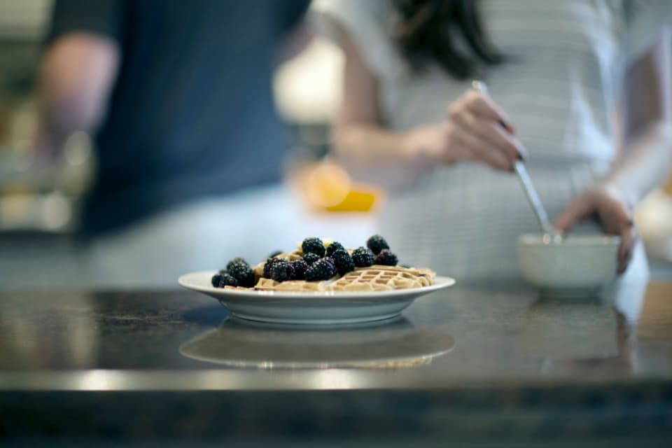 A chef carefully finishing a plate with fresh berries